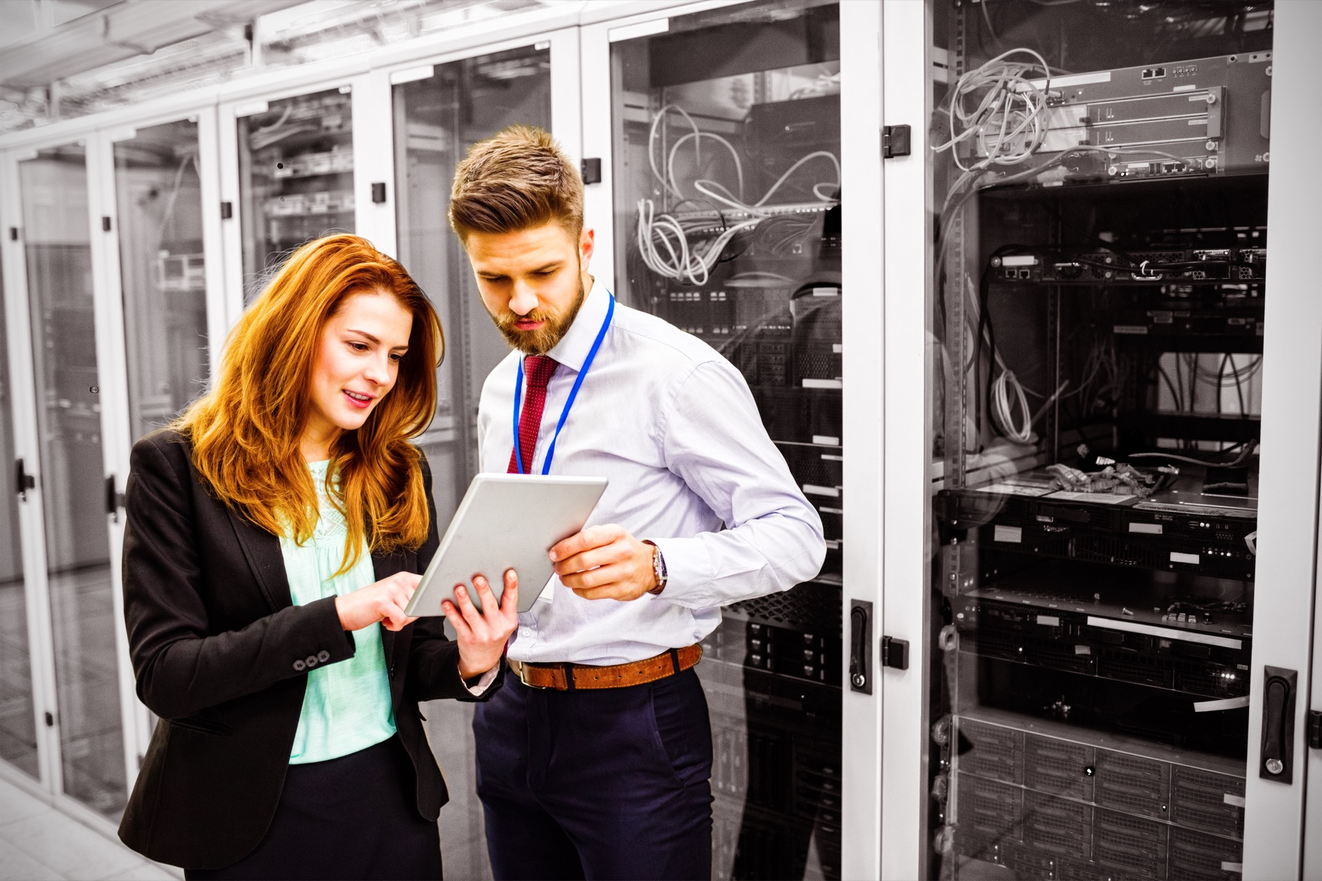 Technicians using digital tablet while analyzing server in server room